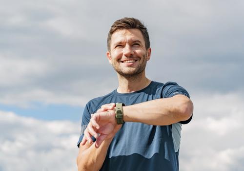 Man checking his fitness watch outdoors before a men's health check