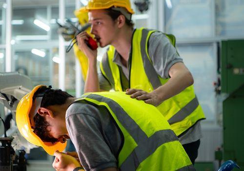 Worker in high visibility clothing holding his shoulder in pain at a work site