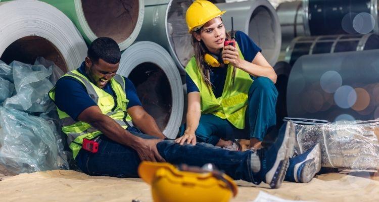 Worker in high visibility clothing holding his shoulder in pain at a work site